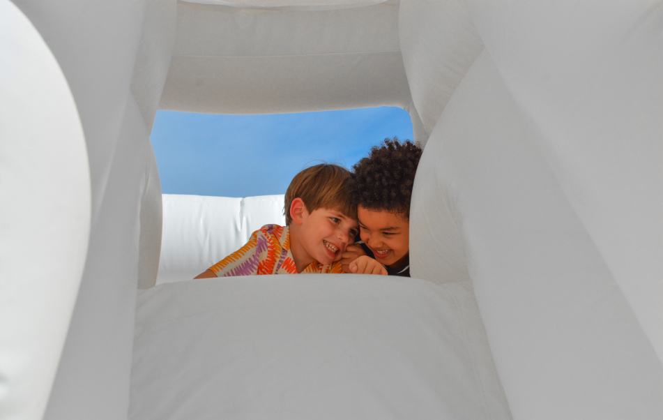 dos niños sonriendo en un castillo hinchable blanco