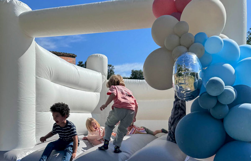 niños divirtiendose en castillo hinchable con guirnalda de globos de colores